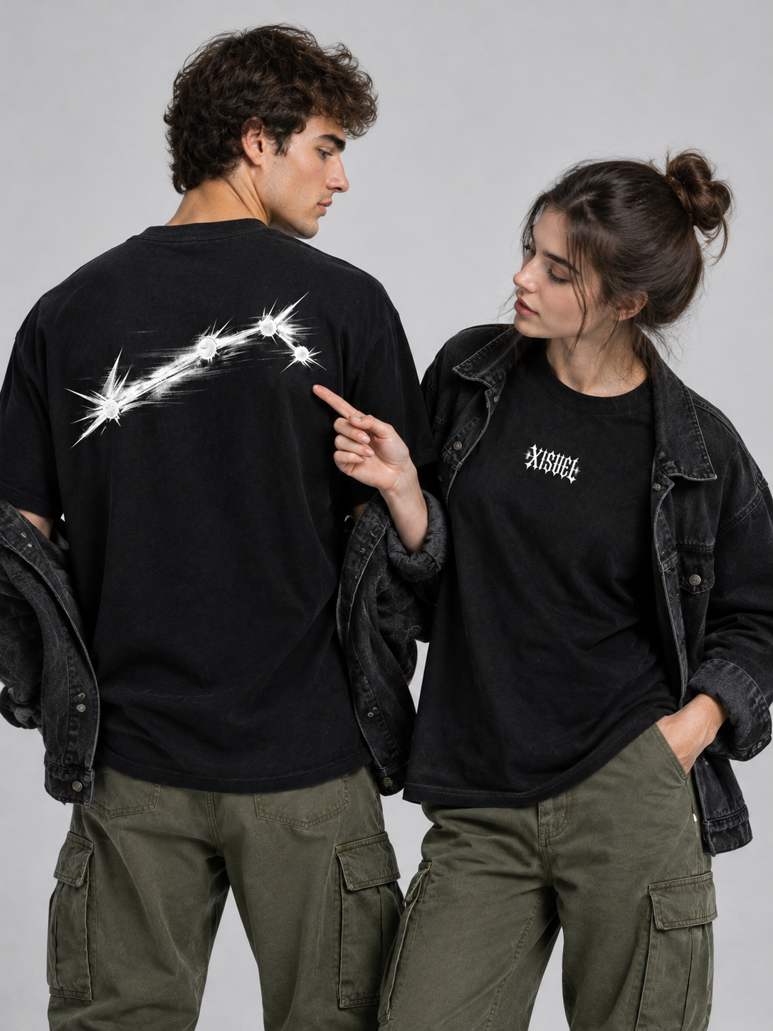 Couple wearing matching black XISVEL graphic tees, back constellation print in focus