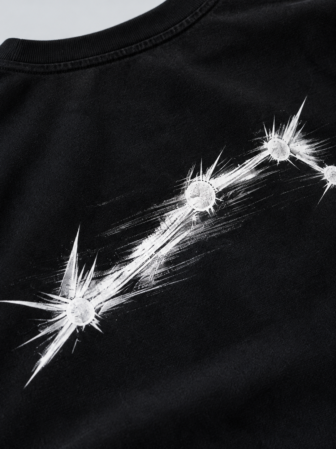 Close-up of the white Aries constellation back print on black cotton fabric