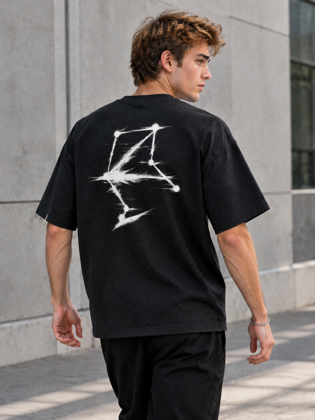 Model walking past minimalist concrete architecture wearing the black Libra constellation graphic tee, back print visible